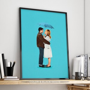 May include: A framed art print showing a couple embracing under a light blue umbrella against a bright turquoise background. The man wears a brown jacket and jeans, while the woman is in a white dress. The print is labeled "COLOR & BLACK-WHITE".