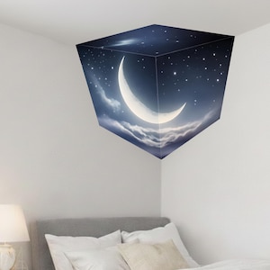May include: A decorative wall decal featuring a crescent moon, stars, and clouds against a dark blue sky. The design is applied to a cube shape, creating a 3D effect. The decal is placed in the corner of a room, above a bed with white pillows.