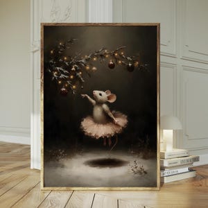 Op de afbeelding: Een ingelijste kunstdruk toont een muisballerina in een roze tutu, die naar ornamenten aan een besneeuwde tak reikt. Het kunstwerk heeft een donkere, sfeervolle esthetiek met warme verlichting en een vleugje fantasie.