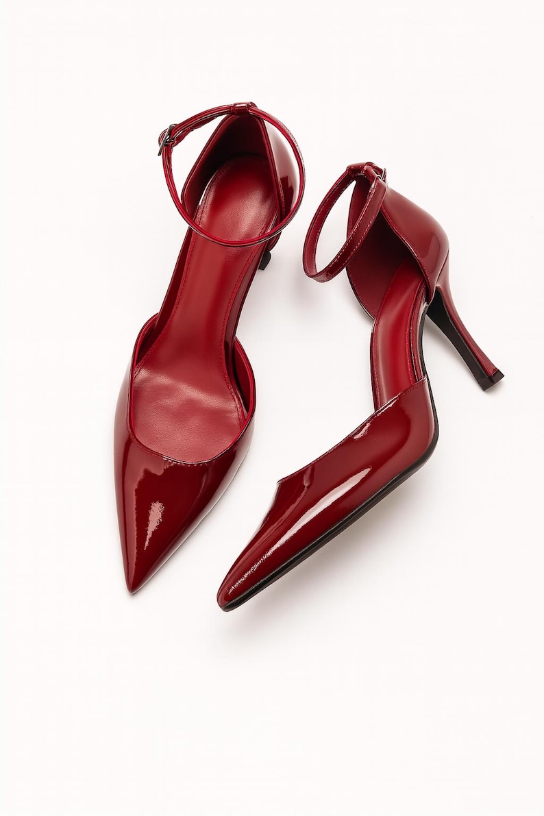 May include: A pair of red patent leather high heels with pointed toes and ankle straps. The shoes have a stiletto heel and a glossy finish, set against a white background. The heels are approximately 3 inches high.