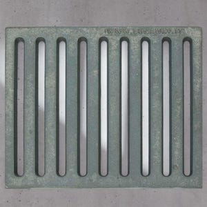 Peut inclure: Une grille métallique rectangulaire grise et patinée avec des fentes verticales. La grille a une surface texturée et le texte "www.lunaway.it" est visible le long du bord supérieur. Le design est simple et industriel.