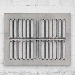 Può includere: Una griglia di ventilazione rettangolare in metallo grigio con un design simmetrico. Presenta una serie di fessure verticali arrotondate disposte su due file, separate da una barra orizzontale. L'estetica generale è industriale e minimalista.