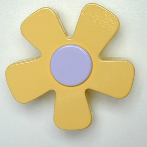 May include: A decorative flower-shaped object with a light yellow exterior and a lavender center. The flower has five petals and a glossy finish, creating a cheerful and playful aesthetic. The design is simple and modern.