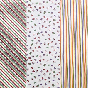 May include: Three different wrapping paper designs. One has diagonal red, green, and white stripes. Another has a white background with Santa faces, gifts, and the text "HO". The third has vertical orange, purple, and green stripes.