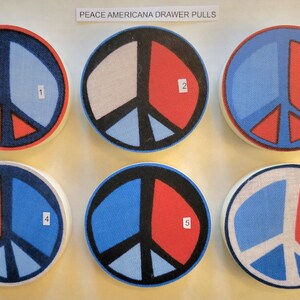 May include: Six round peace sign drawer pulls in red, white, and blue Americana colors. The pulls are numbered 1 through 6.