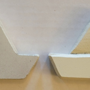 May include: Two wooden sailboat ornaments, one painted white and the other painted white with a beige sail. The white sailboat has a small hole in the center.