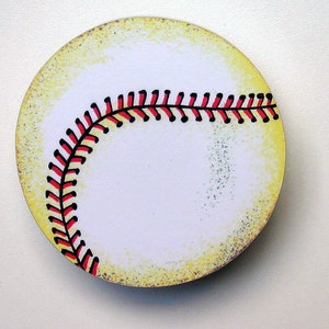 May include: A white baseball with red and black stitching. The baseball has a yellowed, distressed look.