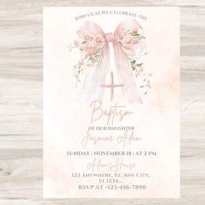 Op de afbeelding: Een doopuitnodiging met een aquarelontwerp. De uitnodiging heeft een roze strik met bloemaccenten, een kruis en het woord "Doop". De tekst bevat de naam "Jasmine Adam", datum, tijd en locatiegegevens.