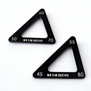 May include: Two black, triangular racing gauges with white numbers and the text "MD SIM RACING". The gauges have numbers from 45 to 80. The gauges are set against a white background.