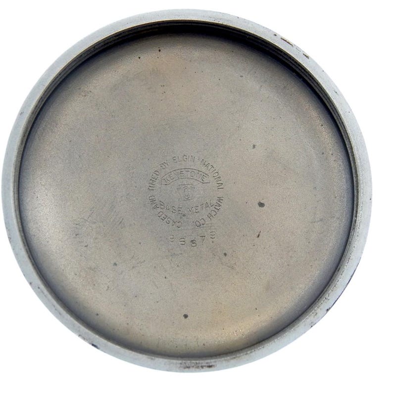 K&ouml;nnte beinhalten: Nahaufnahme der Innenseite eines Vintage-Uhrengeh&auml;uses. Das Geh&auml;use besteht aus silberfarbenem Metall mit kreisf&ouml;rmiger Form. Der Text "Keystone" und "Elgin National Watch Co." sind sichtbar, zusammen mit der Nummer "33679".