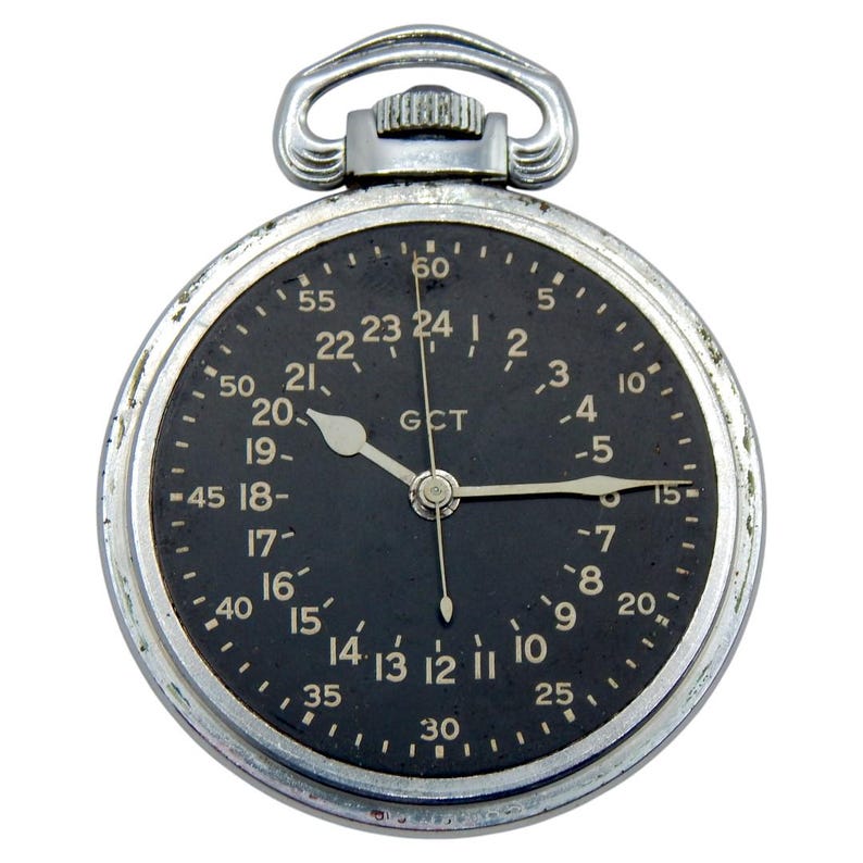 K&ouml;nnte beinhalten: Eine Vintage-Taschenuhr mit schwarzem Zifferblatt und silbernem Geh&auml;use. Die Uhr hat wei&szlig;e Ziffern und Zeiger, mit dem Text "GCT" in der Mitte. Sie hat oben eine Schlaufe zum Anbringen einer Kette.