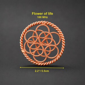 Op de afbeelding: Een cirkelvormig koperkleurig metalen ornament met een gedraaide touwachtige buitenrand en een ingewikkeld intern patroon van in elkaar grijpende cirkels. De tekst "Flower of life 188 MHz" en een maat van 5,5 cm zijn zichtbaar.