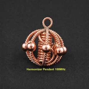 Peut inclure: Un pendentif de couleur cuivre composé d'un cylindre central en fil torsadé entouré d'anneaux en fil torsadé et de petites perles sphériques. Le pendentif possède une boucle supérieure et porte le texte Harmonizer Pendant 188MHz en bas.
