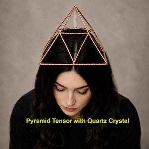Puede incluir: Un tensor piramidal de alambre de cobre con un marco de metal trenzado y un cristal de cuarzo transparente suspendido en el vértice. La estructura es geométrica con paneles triangulares e incluye el texto Pyramid Tensor with Quartz Crystal.