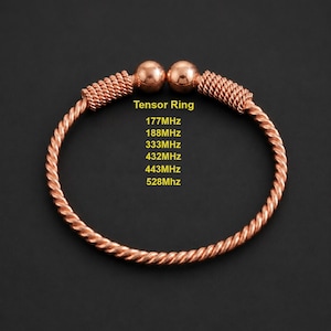 May include: A copper-colored metal bracelet featuring a twisted wire design with two spherical ends. The text "Tensor Ring" is printed in yellow, followed by a list of frequencies: 177MHz, 188MHz, 333MHz, 432MHz, 443MHz, and 528MHz in yellow text.