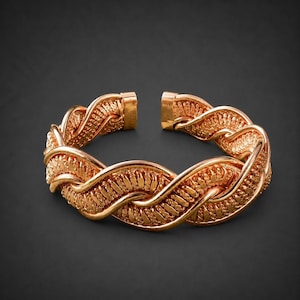 Può includere: Un bracciale a fascia color rame caratterizzato da un design intrecciato e ritorto. La superficie metallica presenta un motivo testurizzato simile a una corda lungo tutto il cinturino, che risulta aperto sul retro con una finitura lucida.