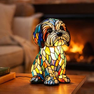 May include: A colorful stained glass dog lamp with a detailed design. The lamp features a variety of colors, including blue, yellow, orange, and green. The lamp is sitting on a wooden table. The lamp is approximately 10 inches tall.