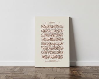 May include: A rectangular canvas print featuring Arabic calligraphy in brown against a cream background. The text is arranged in vertical lines, with each line containing multiple words. The print is displayed on a white wall above a wooden floor.