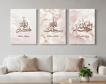 May include: Three framed canvas art pieces with Arabic calligraphy in brown script. The backgrounds feature soft, blurred floral patterns in shades of pink and white. The text includes "Allahu Akbar", "Subhan Allah", and "Al Hamdu Lillah".