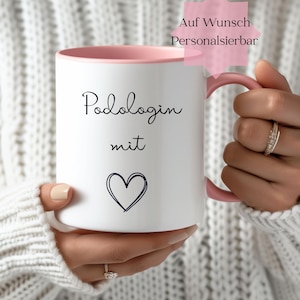 Könnte beinhalten: Weißer Keramikbecher mit rosa Innenraum und Henkel. Der Becher trägt die Worte "Podologin mit" in schwarzer Schrift sowie ein handgezeichnetes blaues Herz. Ein rosa sternförmiges Etikett lautet "Auf Wunsch Personalisierbar".