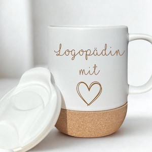 Könnte beinhalten: Ein weißer Keramikbecher mit Henkel und passendem weißen Deckel. Der Becher hat einen braunen Korkboden und den braunen Schriftzug Logopädin mit, gefolgt von einem handgezeichneten Herzumriss. Das Design ist auf der weißen Oberfläche zentriert.