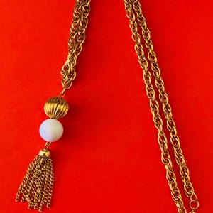 Fritter with this vintage textured gold tone layered chain and white bead with chain tassel necklace