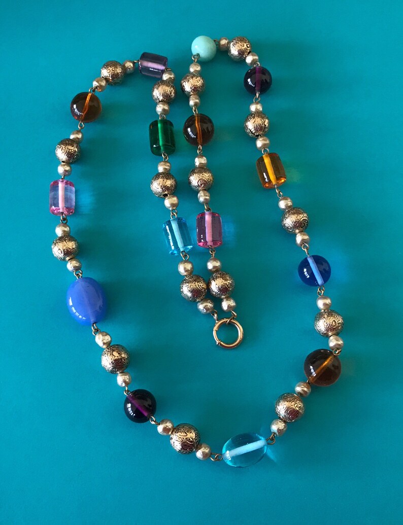 May include: A colorful beaded necklace with silver round beads and various colored glass beads, including blue, green, purple, pink, and orange. The necklace has a silver clasp.