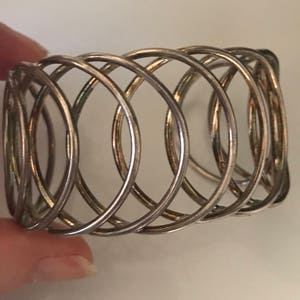 May include: Silver metal napkin ring with a woven design.
