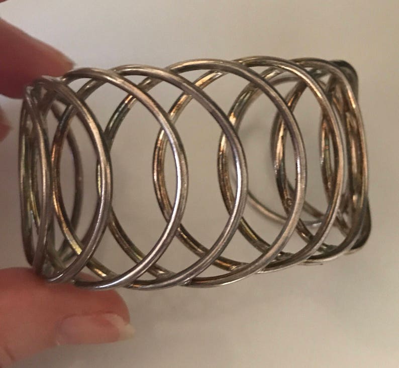 May include: Silver metal napkin ring with a woven design.