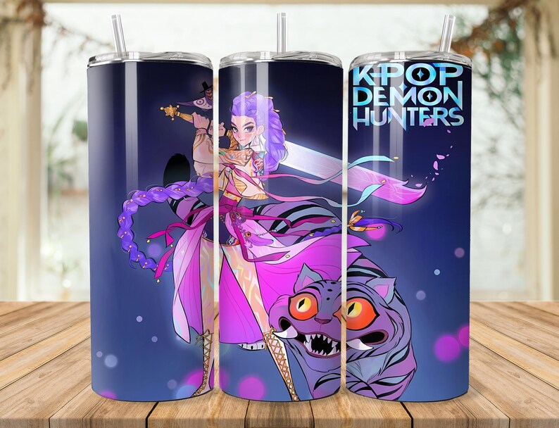 Puede incluir: Tres vasos de acero inoxidable con un dise&ntilde;o envolvente que presenta un personaje de anime de pelo morado con una espada, un tigre y el texto "KPOP DEMON HUNTERS" sobre un fondo azul degradado. Cada vaso tiene una pajita plateada.