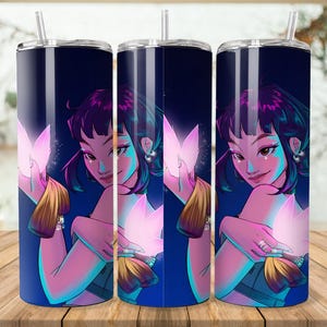 Puede incluir: Un juego de tres vasos de acero inoxidable con una ilustraci&oacute;n envolvente de una mujer con cabello p&uacute;rpura y una flor brillante. El dise&ntilde;o presenta un fondo azul oscuro con acentos rosas y turquesas. Cada vaso incluye una pajita.