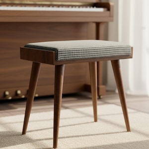 May include: A wooden piano bench with a houndstooth patterned seat cushion. The bench has four angled legs and a rectangular frame. The wood has a warm, brown tone, and the bench sits on a cream-colored rug.