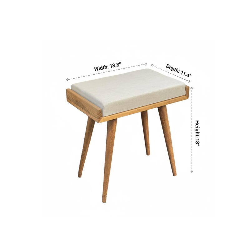 Puede incluir: Un taburete de madera con un asiento rectangular y acolchado. El asiento es de color beige claro, y el marco y las patas son de color madera natural. El taburete mide 45.7 cm de alto, 47.8 cm de ancho y 29 cm de profundidad. Las patas est&aacute;n inclinadas hacia afuera.