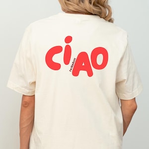 Könnte beinhalten: Cremefarbenes T-Shirt mit dem Wort "CIAO" in großen, roten, abgerundeten Buchstaben auf dem Rücken. Das Wort "PATRIARCHY" ist vertikal in kleineren roten Buchstaben aufgedruckt. Das Shirt hat kurze Ärmel und eine lässige Passform.