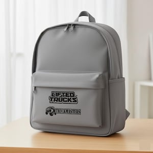 May include: A gray backpack with a front pocket and side pocket. The front pocket features the text "LIFTED TRUCKS" above a graphic of a truck and the text "TRUCKMASTERS". The backpack has a top handle and two zippered compartments.
