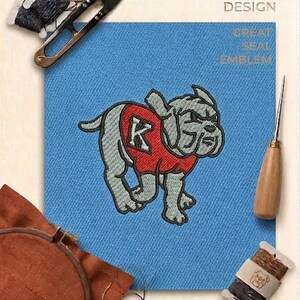 May include: A digital embroidery design featuring a grey bulldog wearing a red sweater with a white letter K, stitched onto light blue fabric. The image includes embroidery scissors, thread spools, and an awl, with text reading PREMIUM EMBROIDERY DESIGN GREAT SEAL EMBLEM DIGITAL FILE MULTI-FORMAT.