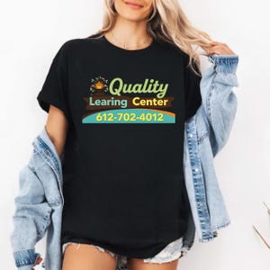 May include: Black t-shirt with the words "Quality Learning Center" in green and yellow, with a house graphic. The phone number 612-702-4012 is printed below the text in yellow and blue.