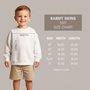 May include: A young child wearing a white sweatshirt and khaki shorts. A size chart for Rabbit Skins sweatshirts is displayed, with measurements in inches. The chart includes sizes 2T through 7T, with width and length measurements.