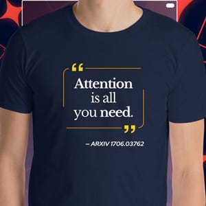 May include: Dark blue t-shirt featuring the quote "Attention is all you need." in white, with yellow framing. The text "- ARXIV 1706.03762" is below. The shirt has a crew neck design.