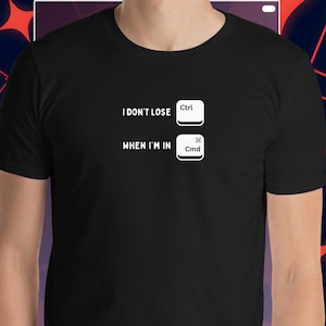 May include: Black t-shirt featuring white text and keyboard key graphics. The text says "I DON'T LOSE Ctrl WHEN I'M IN Cmd". The Ctrl and Cmd keys are shown as white rectangles. The shirt is a short-sleeved crew neck.