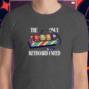 May include: Dark gray t-shirt with the text "THE ONLY KEYBOARD I NEED." The graphic features a colorful keyboard design with the letters "L G T M" on the keys, connected by a cable and USB plug.