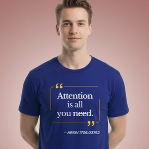May include: A royal blue short-sleeved t-shirt featuring a yellow graphic of quotation marks enclosing the white text "Attention is all you need." Below the quote, the text "– ARXIV 1706.03762" is printed in white on the chest of the garment.