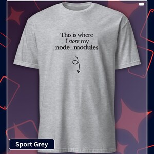 以下が含まれることがあります： 「This is where I store my node_modules」の黒い文字がプリントされたスポーツグレーのTシャツ。黒い矢印が下を指しています。このTシャツは半袖のクルーネックです。