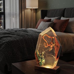 Puede incluir: L&aacute;mpara decorativa en forma de cristal con base de madera. El interior de la l&aacute;mpara presenta un dise&ntilde;o colorido y detallado con un brillo c&aacute;lido. La l&aacute;mpara est&aacute; sobre una mesita de noche de madera oscura.