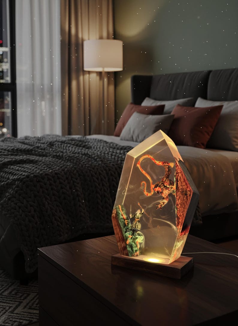 Puede incluir: L&aacute;mpara decorativa en forma de cristal con base de madera. El interior de la l&aacute;mpara presenta un dise&ntilde;o colorido y detallado con un brillo c&aacute;lido. La l&aacute;mpara est&aacute; sobre una mesita de noche de madera oscura.