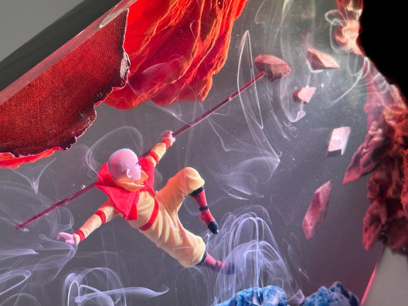 May include: A miniature figure in a yellow and red outfit, holding a staff, appears to be floating in a smoky, abstract environment. Red and blue elements frame the scene, with floating rock-like shapes.