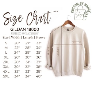 Może przedstawiać: Beżowa bluza unisex Gildan 18000 na wieszaku, z tabelą rozmiar&oacute;w pokazującą wymiary w calach dla szerokości, długości i rękawa. Rozmiary od S do 5XL.