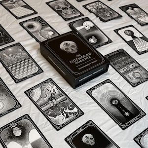 May include: A black oracle deck box with the text "THE EIGENGRAU ORACLE DECK" and several black and white oracle cards. The cards feature detailed illustrations and are spread out on a white surface.