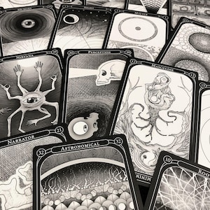 May include: A collection of black and white tarot cards with intricate illustrations. The cards feature surreal imagery, including eyes, skulls, and abstract designs. Text on the cards includes words like "Nirvana," "Perception," and "Astronomical."