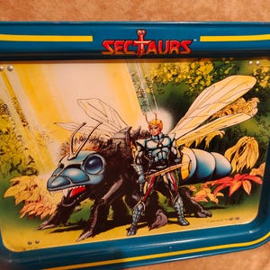 May include: A vintage metal tray with a teal and yellow border. The tray features a colorful illustration of a character from the Sectaurs toy line, with a large insect-like creature and a warrior figure. The Sectaurs logo is at the top.